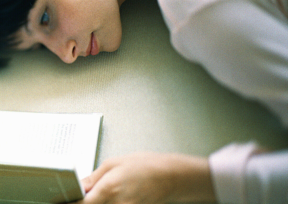 Woman lying down, reading, close-up