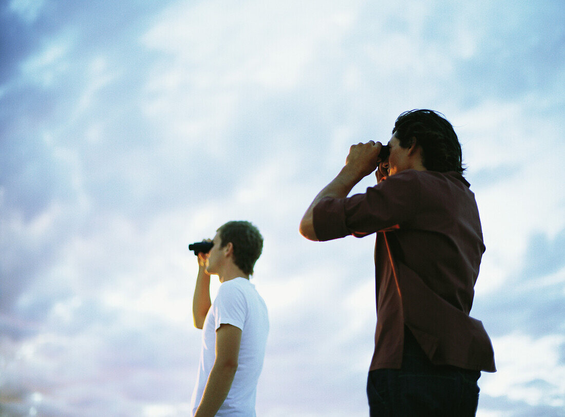 Two people looking through binoculars, low angle view