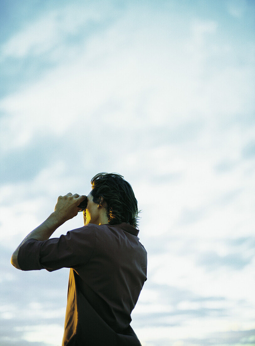 Man looking through binoculars, low angle view