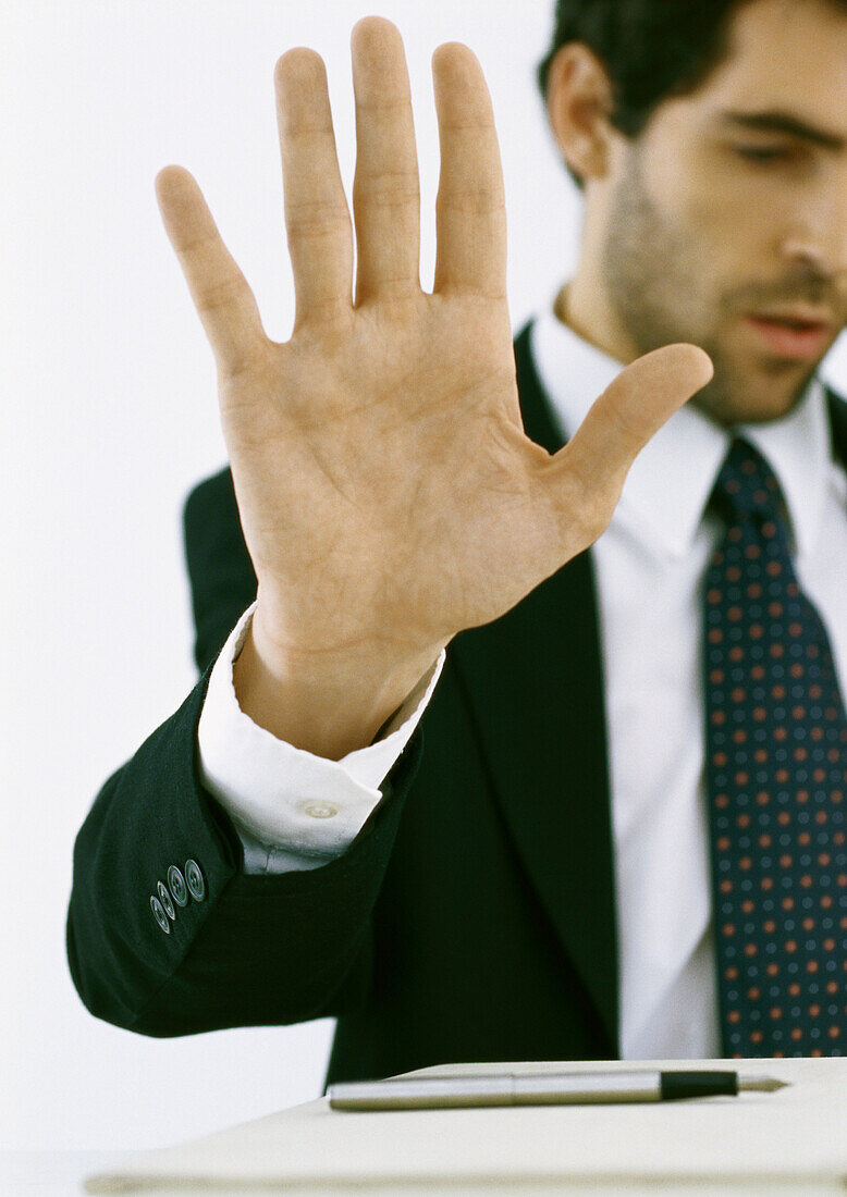 Businessman holding up hand and looking down