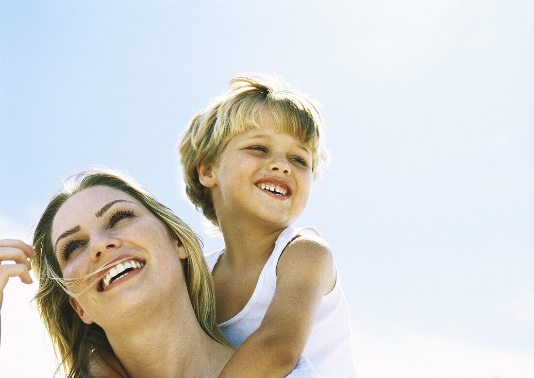 Boy and mother, boy behind mother with arms around her neck, portrait