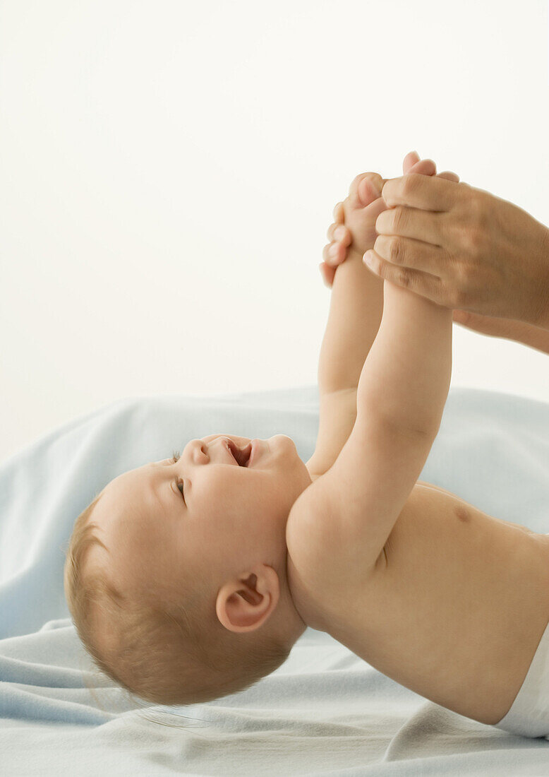 Parent lifting baby by hands. cropped