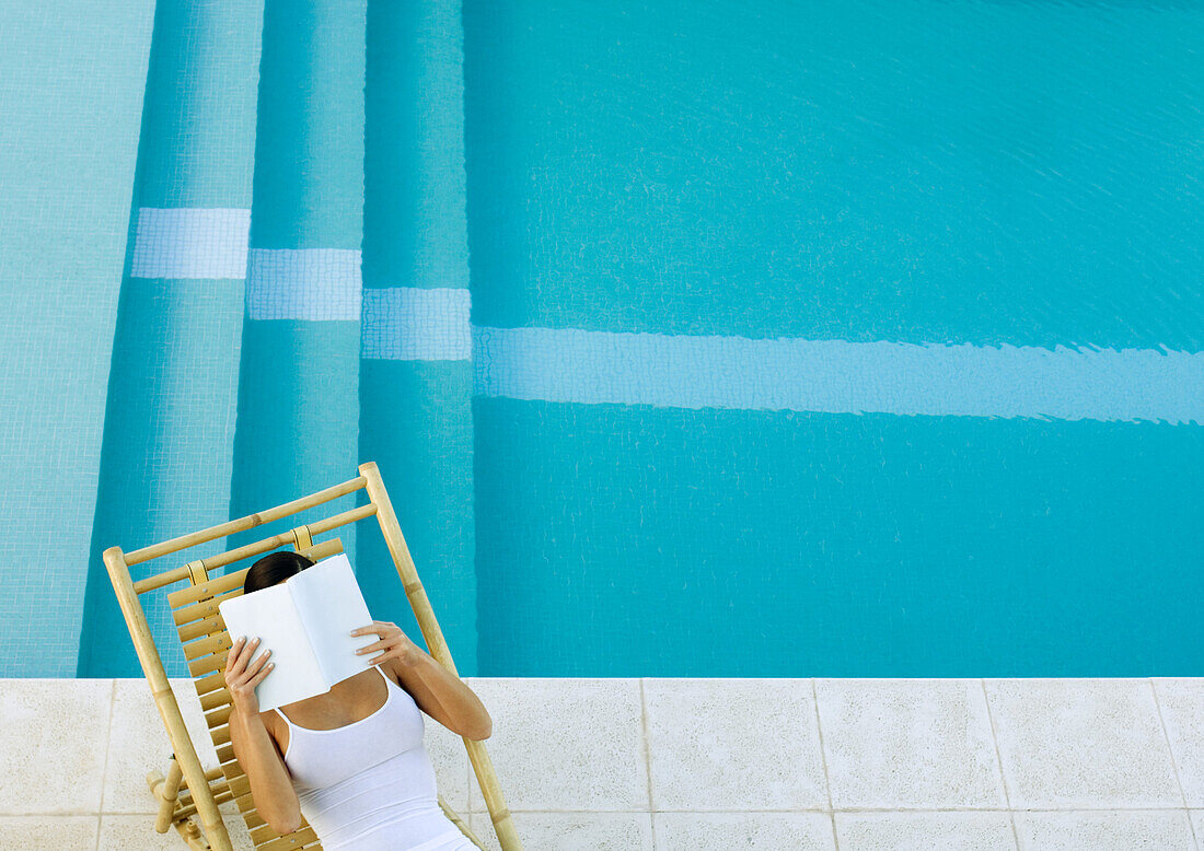 Frau im Liegestuhl am Pool sitzend, lesend, hoher Blickwinkel