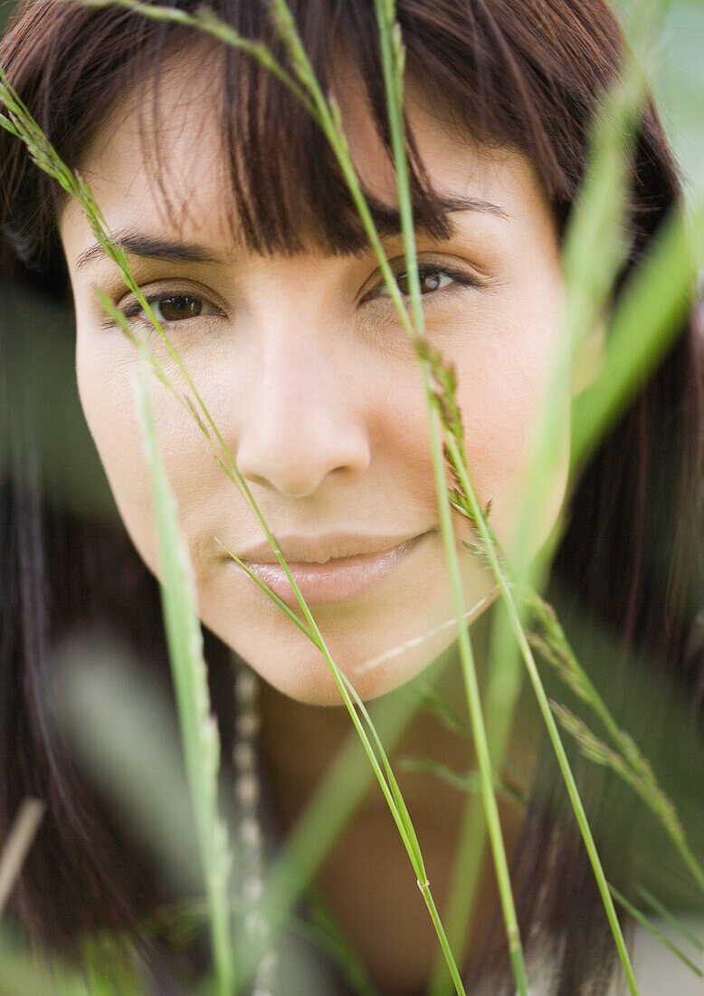 Woman's face seen through blades of grass