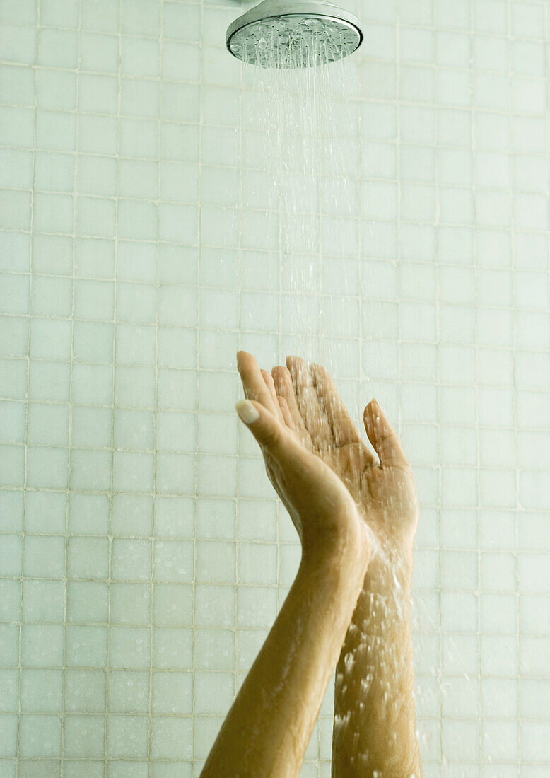 Woman holding up hands under shower