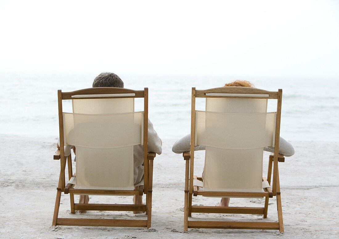 Two people sitting in beach chairs, rear view