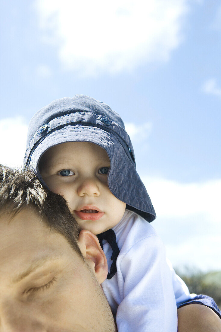 Man carrying baby on shoulders, cropped view