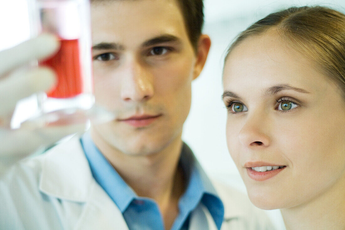 Young male and female lab workers, holding up test tube