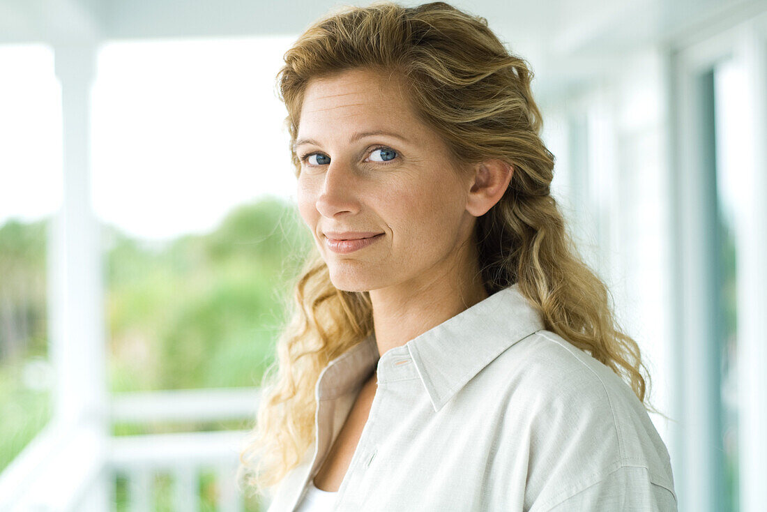 Woman on porch smiling at camera, portrait
