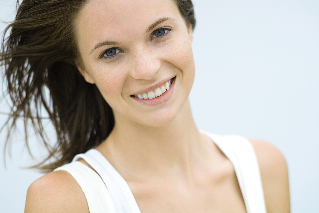 Teenage girl smiling at camera, hair tousled by breeze, portrait