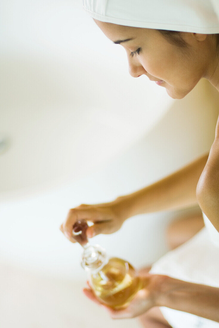 Woman opening perfume bottle, side view, high angle, cropped