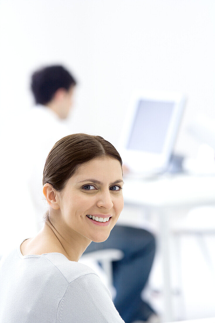 Female office worker, smiling over shoulder at camera