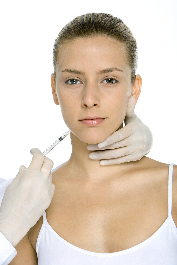 Young woman receiving collagen injection, looking at camera