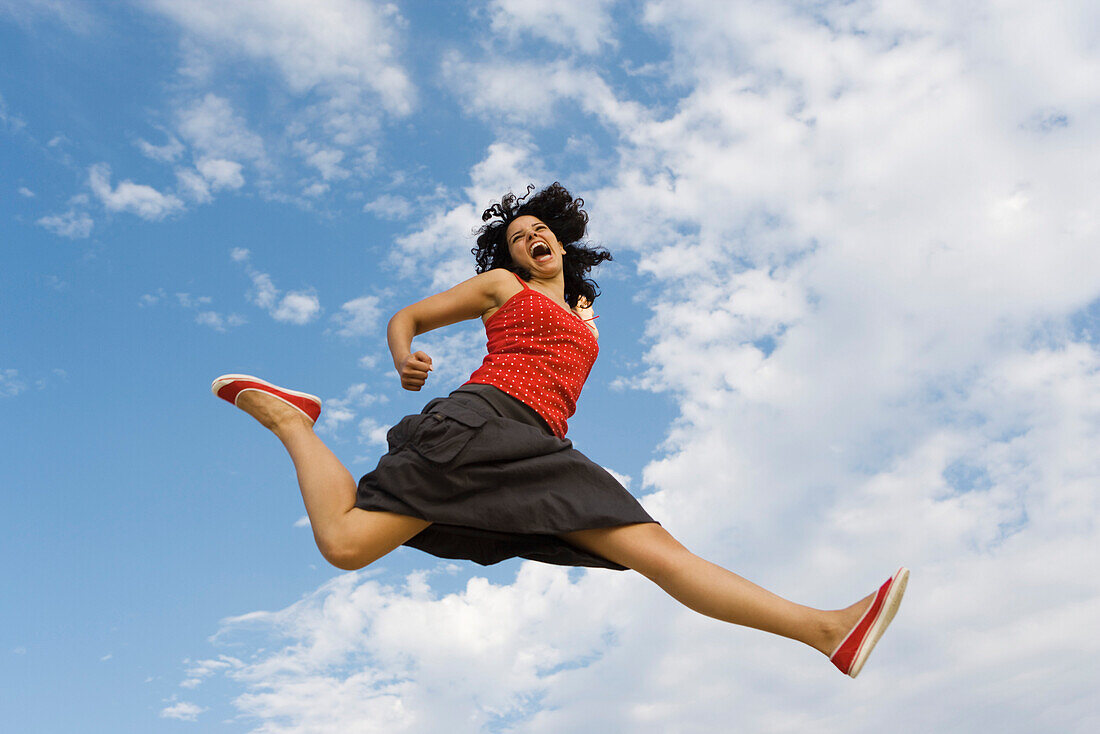 Young woman jumping in midair, low angle view