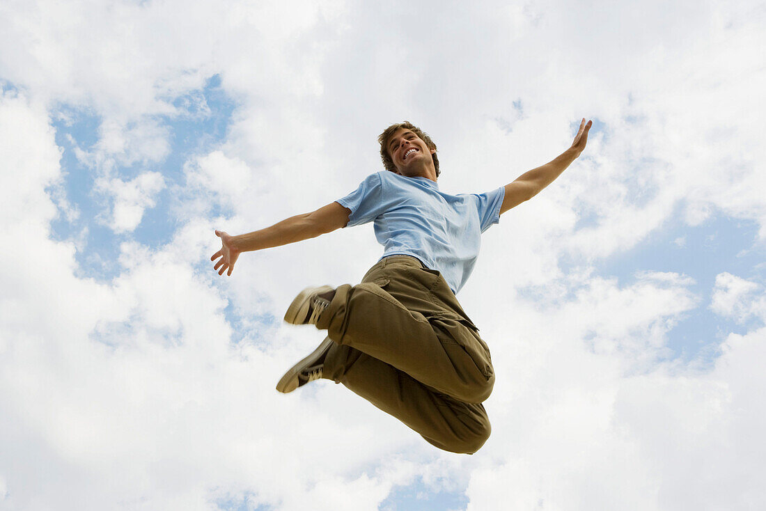 Man jumping joyfully in midair, low angle view
