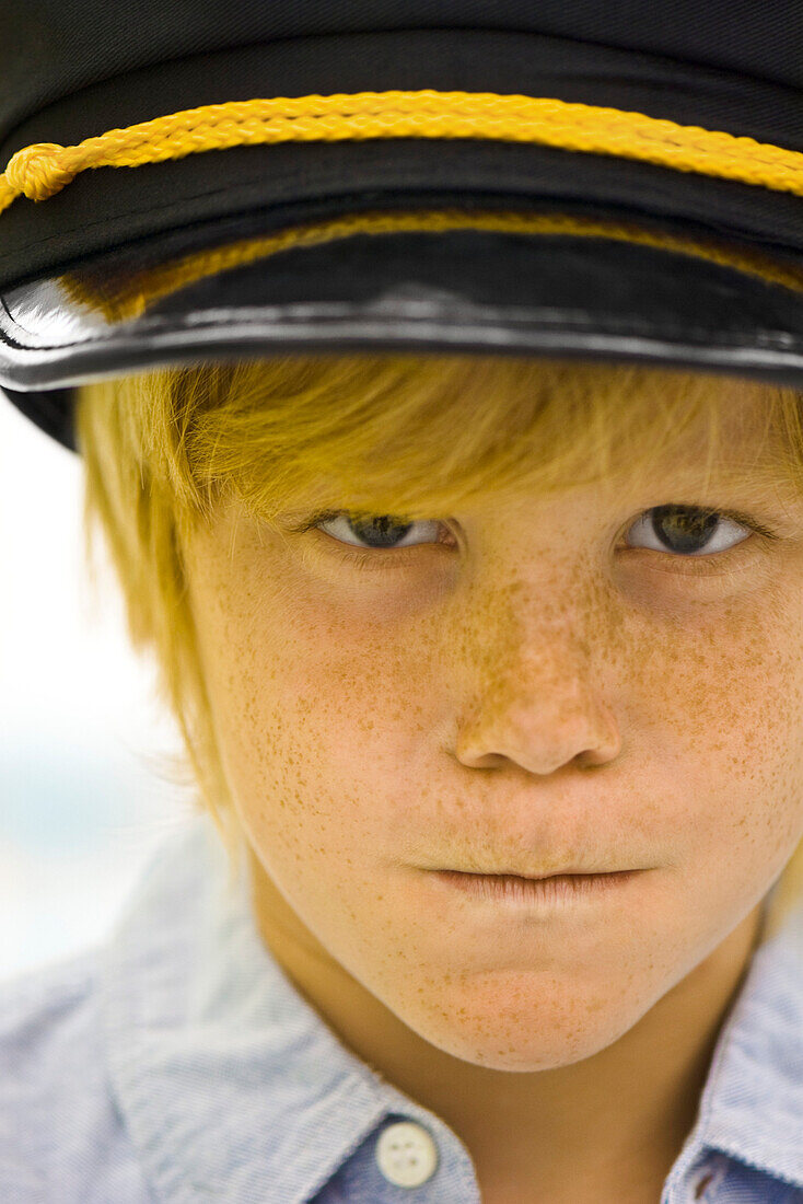 Boy wearing police officer's cap looking sternly at camera