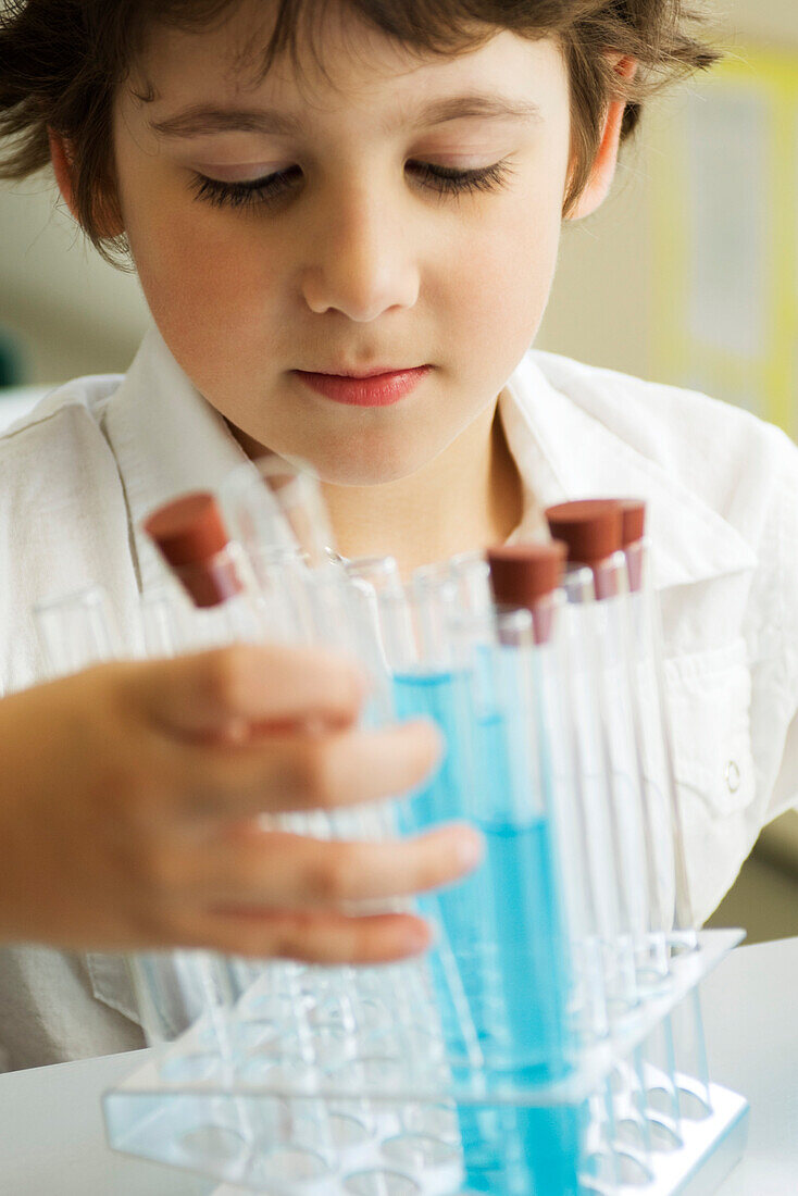Boy placing test tubes in test tube rack