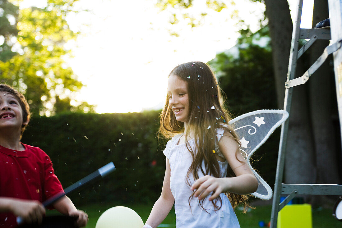 Children having fun under falling confetti