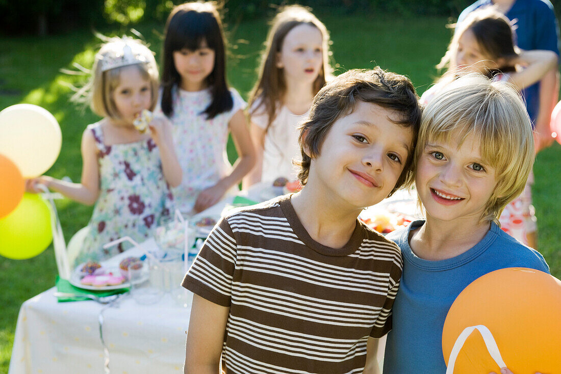 Young friends together at outdoor birthday party, portrait