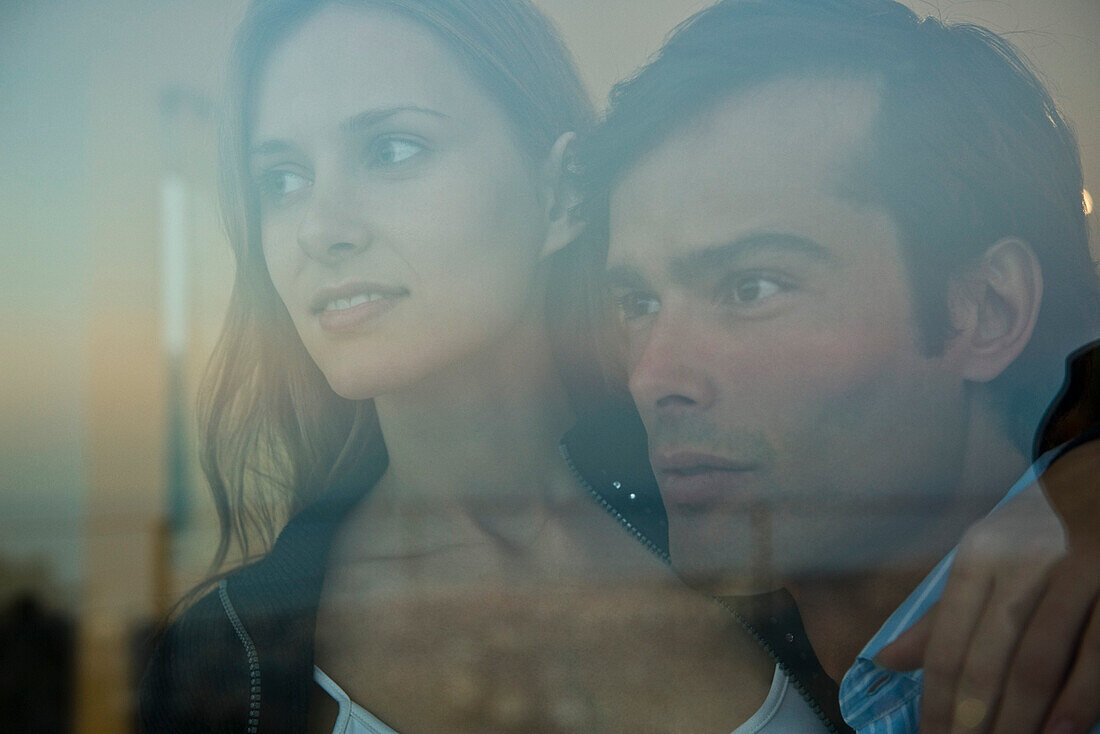 Couple looking through window, portrait