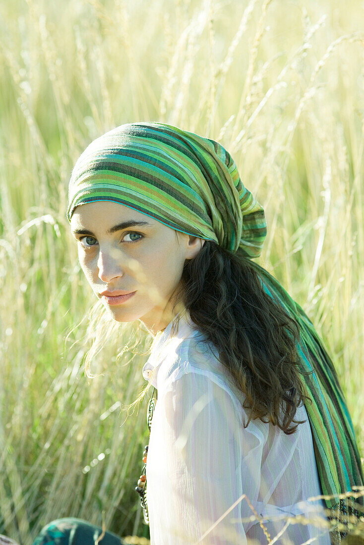 Young hippie woman in field, looking at camera, portrait