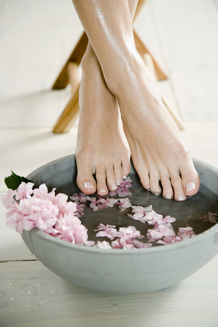 Young woman's feet and floral foot bath