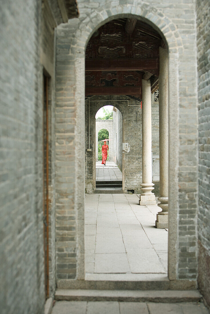 Young woman in traditional Chinese clothing, seen through archway