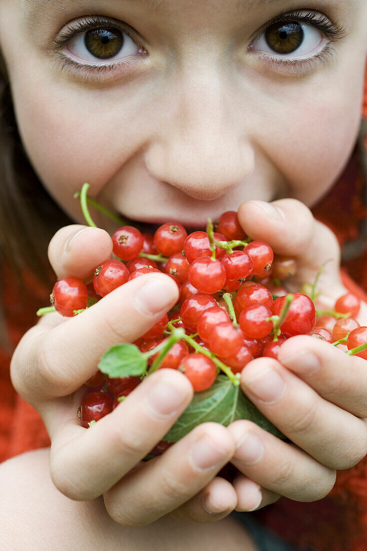 Teenage girl holding up large handful of red currants, close-up