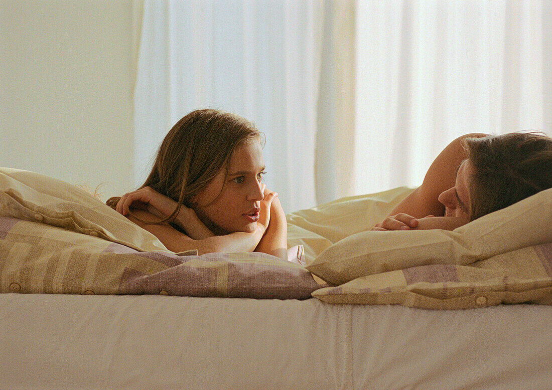 Couple lying in bed talking to each other