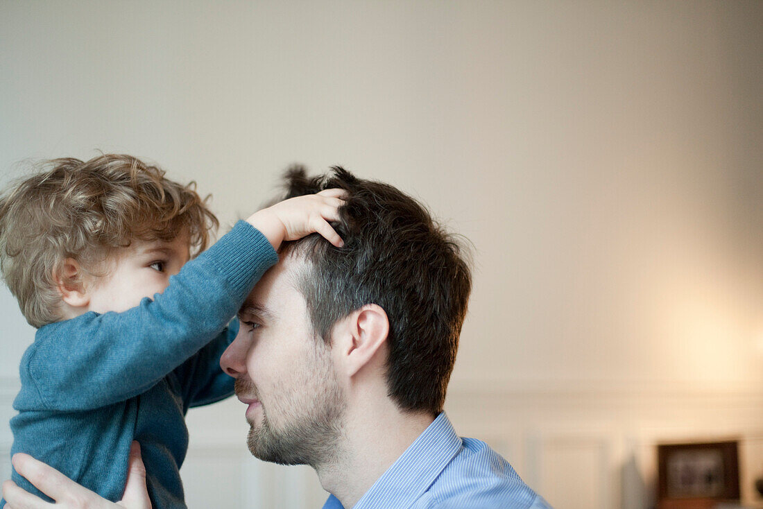 Toddler boy playing with father's hair