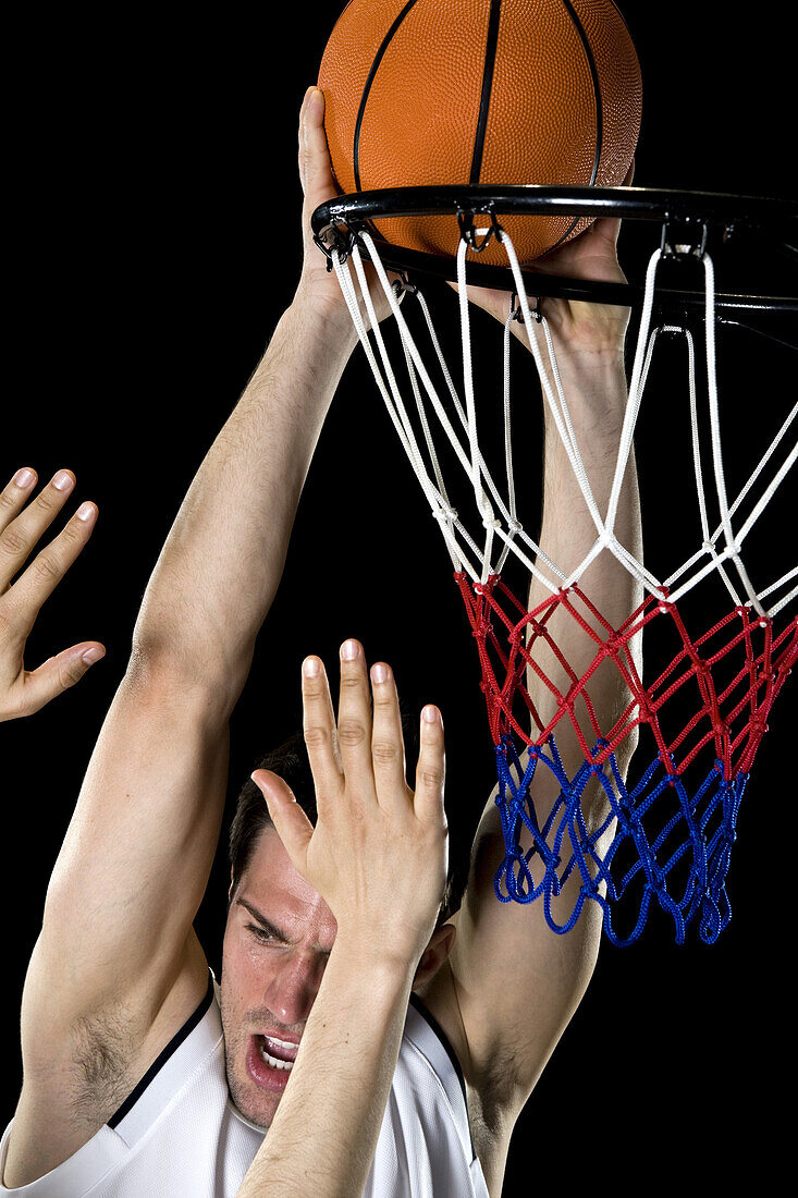 A basketball player trying to make a basket, studio shot