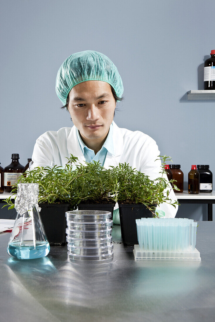 A lab technician staring intently at a plant in a laboratory