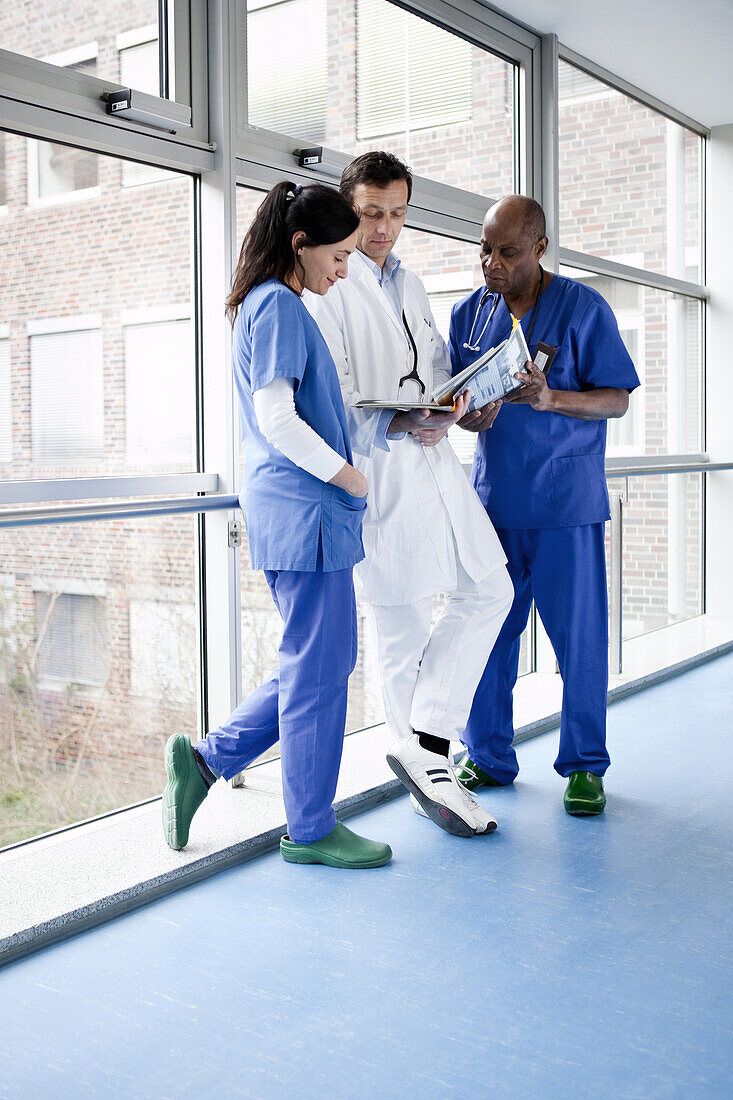 Three medical professionals consulting over a medical file in a hospital