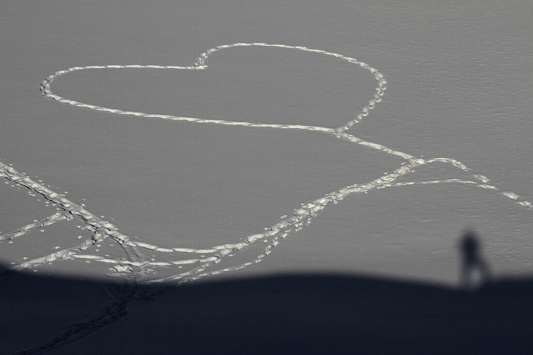 A heart shape stamped out in the snow by footprints