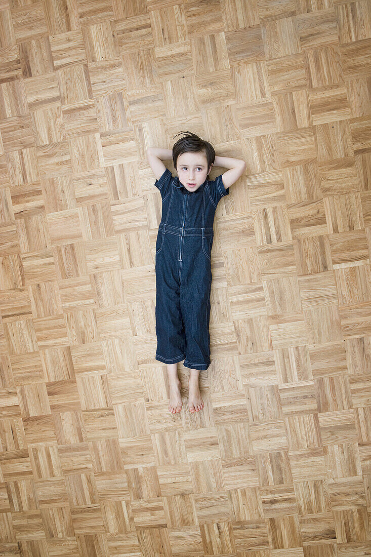 A boy lying on the floor with hands behind his head