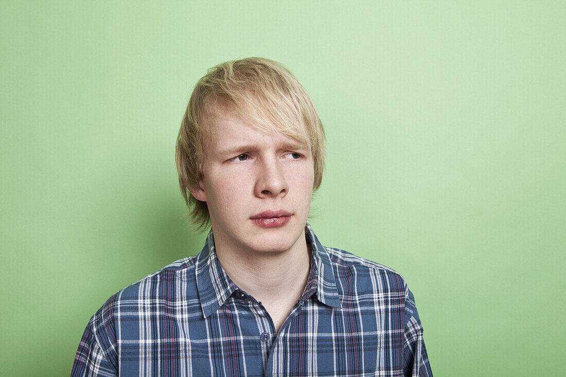 A teenage boy looking off to the side with suspicion, portrait, studio shot