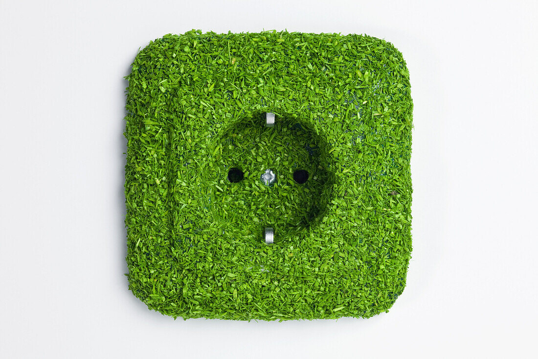 Energy saving electrical wall outlet covered in green grass