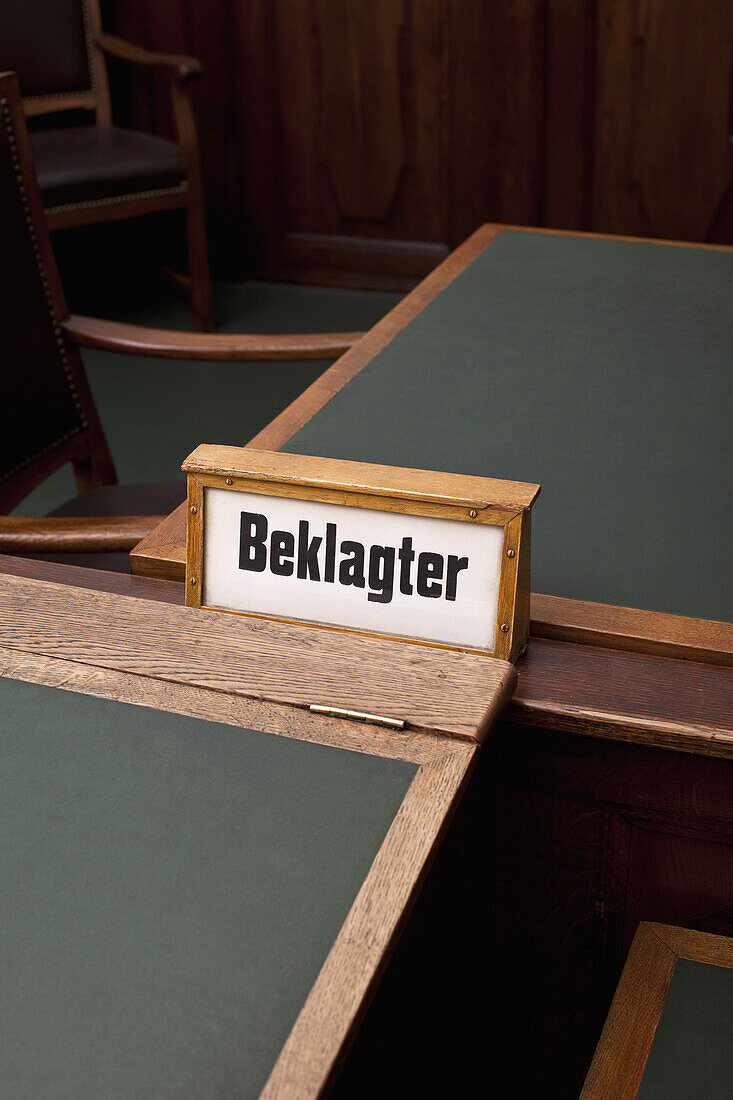 The German word, Beklagter, for defendant on a sign, among some tables and chairs.