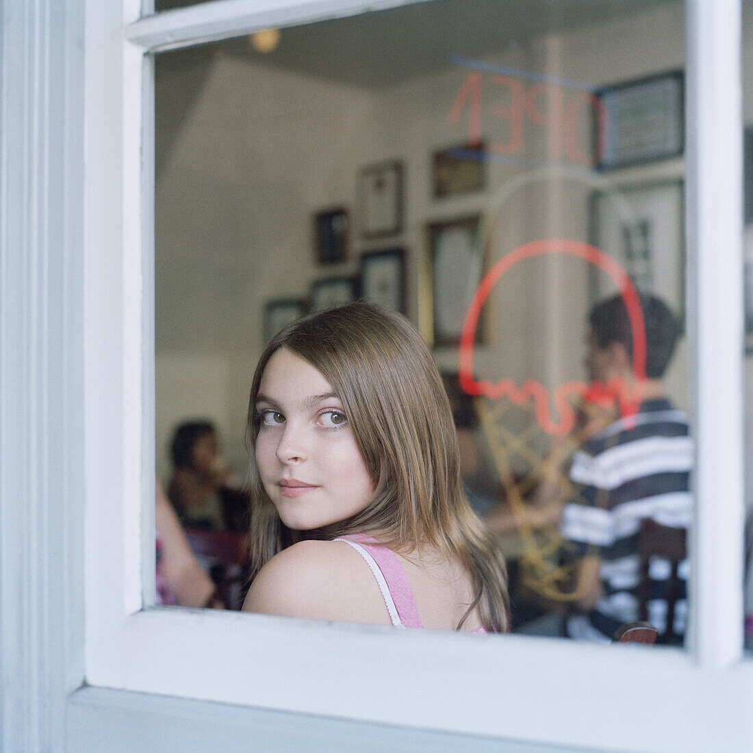 A teenage girl looking through a cafe window