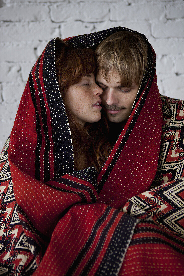 A sensual young couple wrapped in a blanket