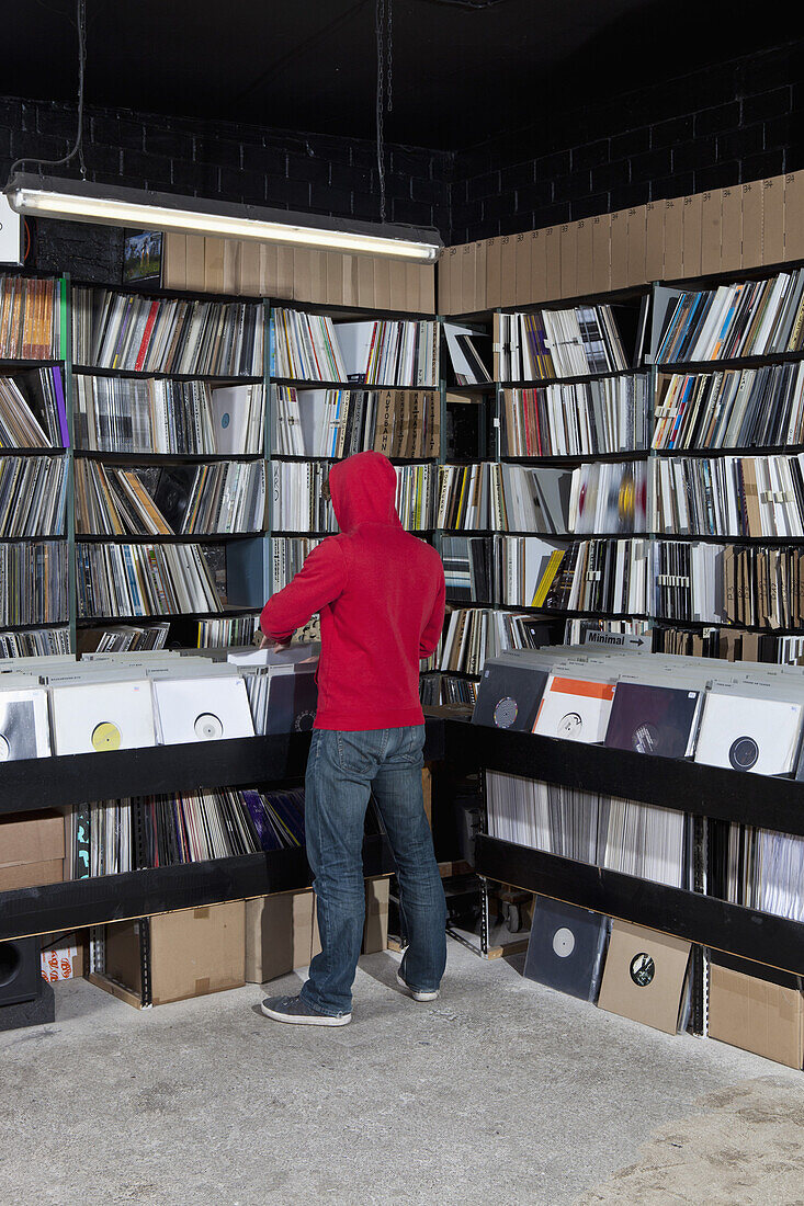 A young man looking through records at a record store, rear view