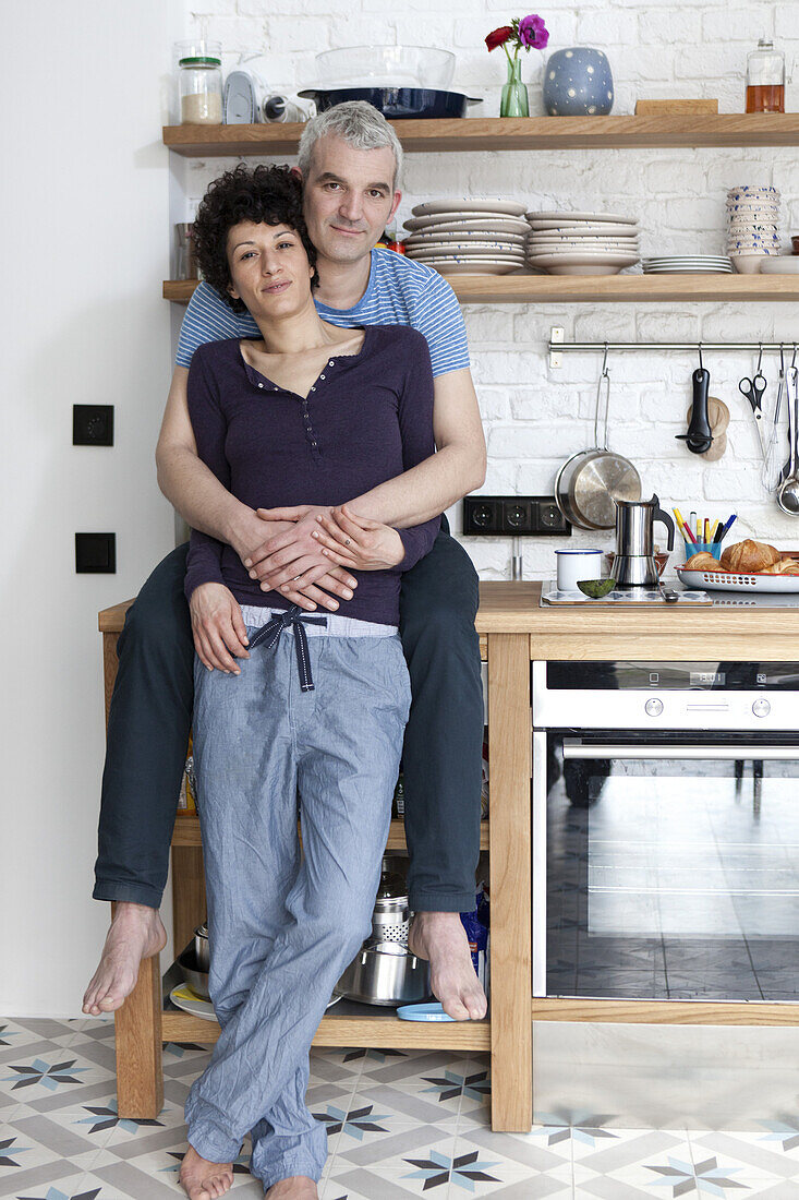 An affectionate smiling mixed age couple in their kitchen