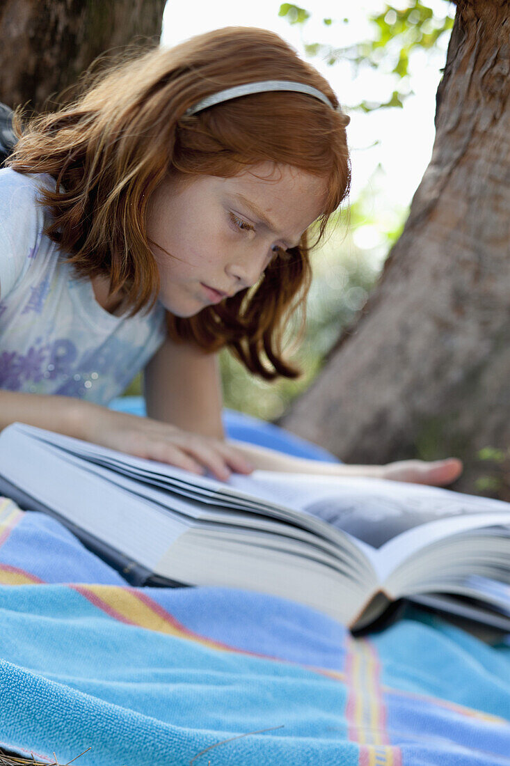 Girl lying down reading book in park