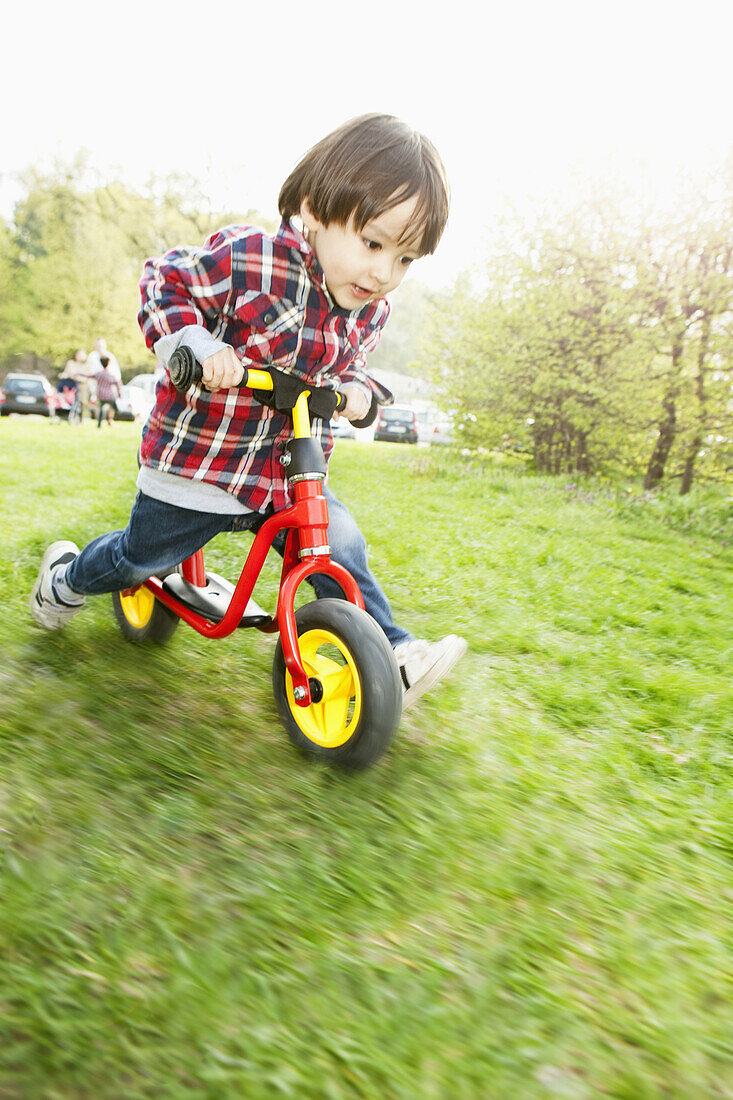 A young boy running on a balance bicycle