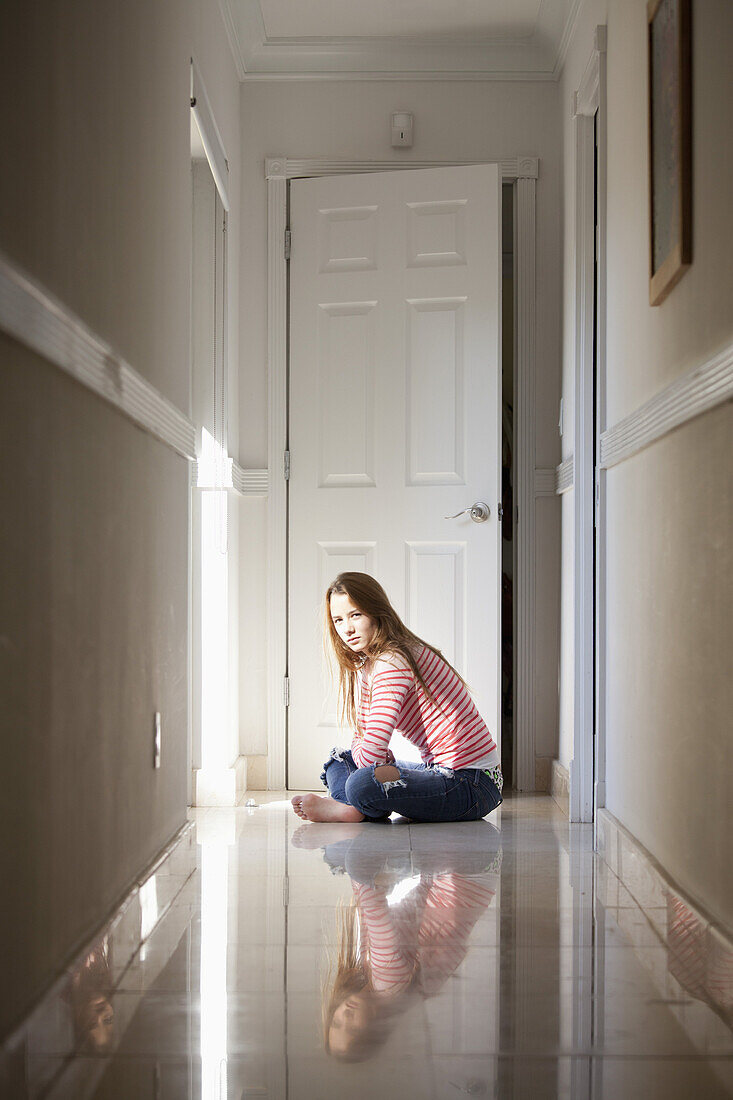 Girl sitting cross-legged in hallway