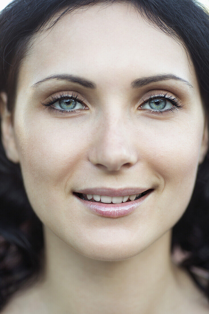 A beautiful young woman smiling into the camera, close-up of face