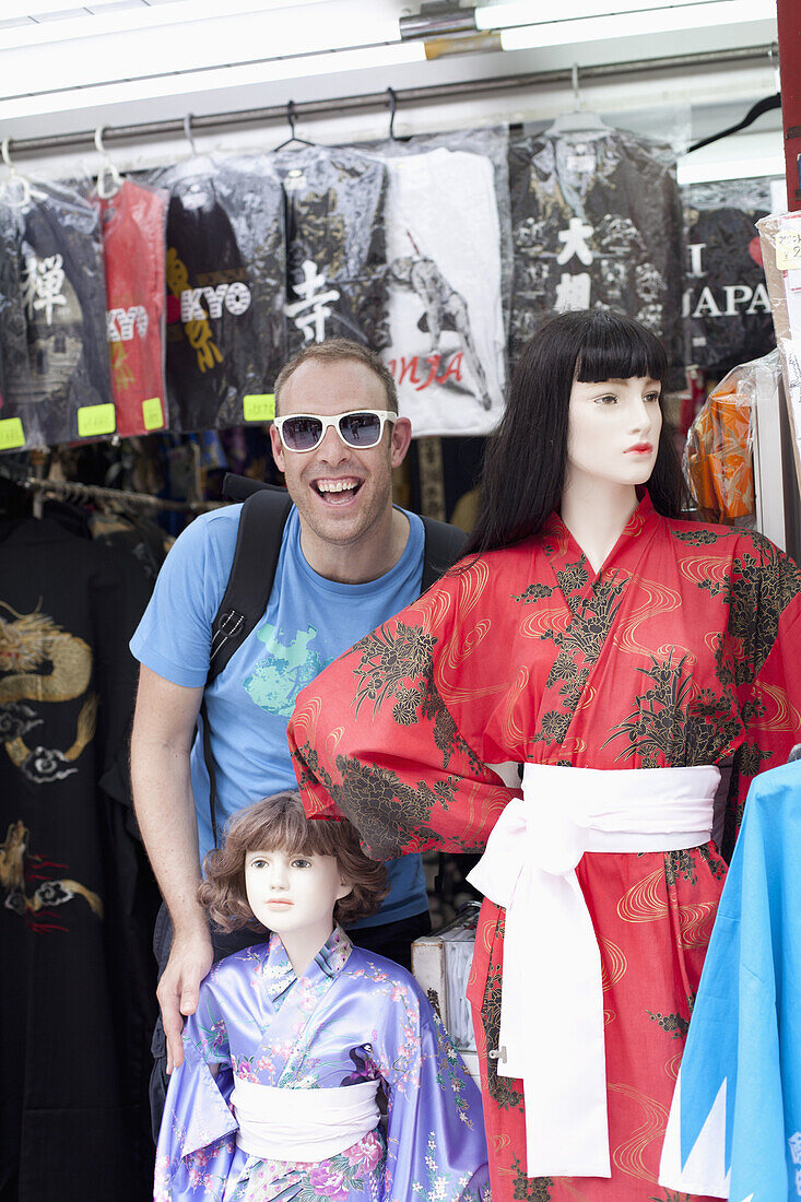 Tourist standing beside female mannequins wearing kimonos