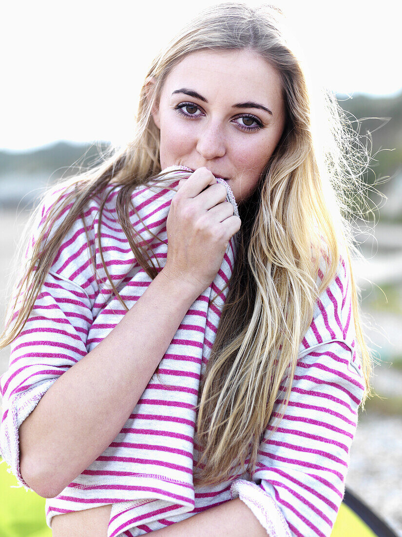 A young woman covering her mouth with her shirt and smiling playfully