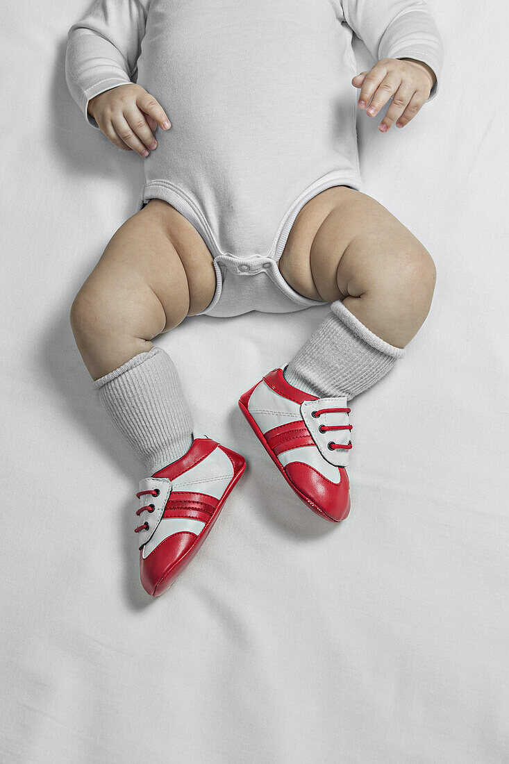 A baby boy wearing baby soccer shoes, waist down