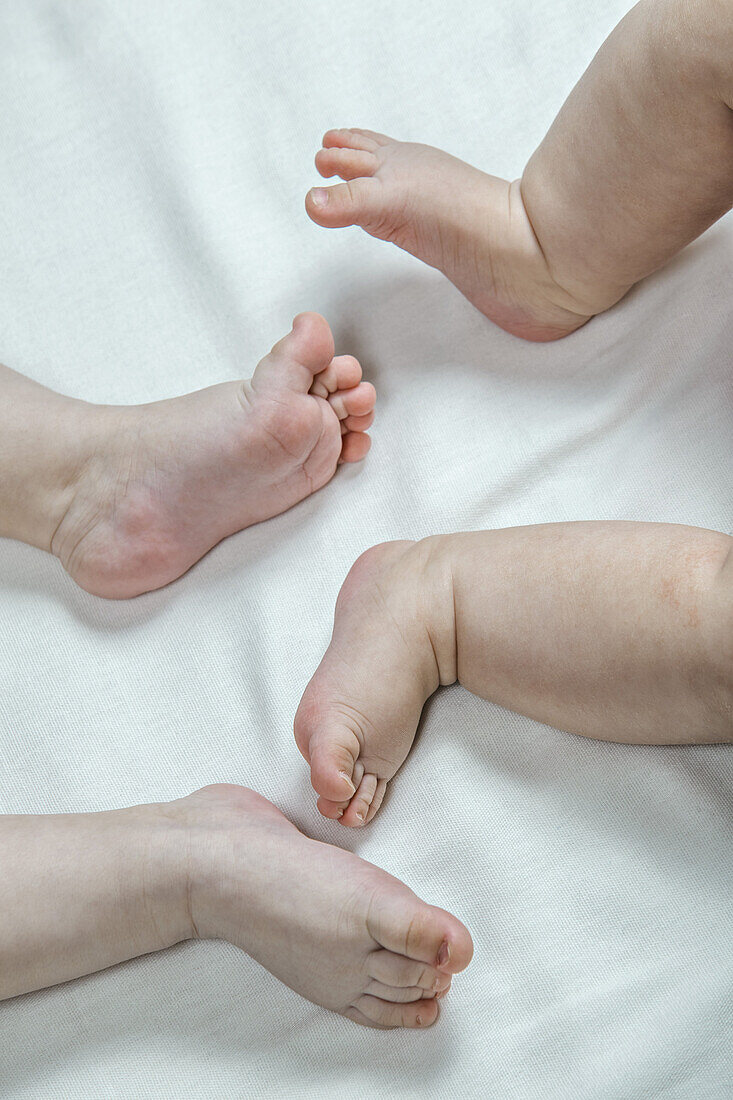 Two barefoot babies lying down, close-up of feet